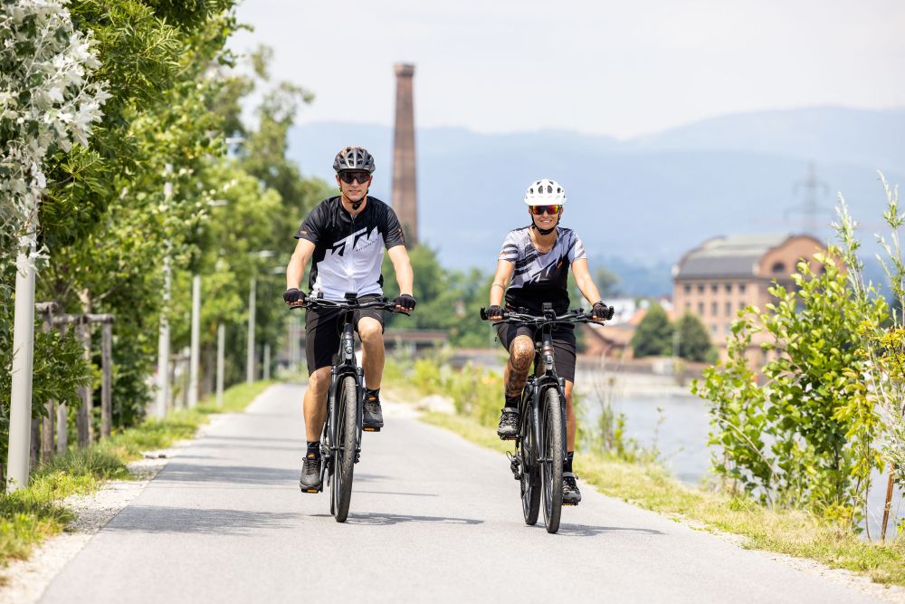 Radfahrer und Radfahrerin von vorne, fahren Straße entlang