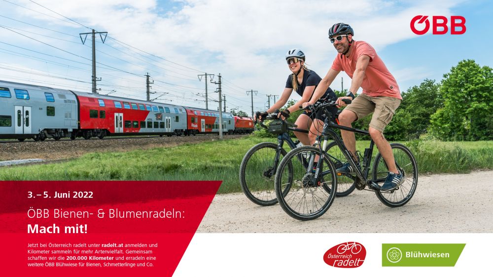 Zwei Radfahrende radeln entlang einer Bahnstrecke.