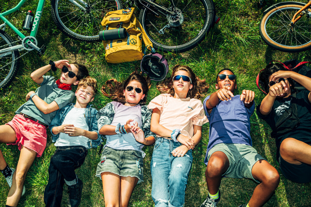 Kinder liegen auf dem Rasen mit woom bikes