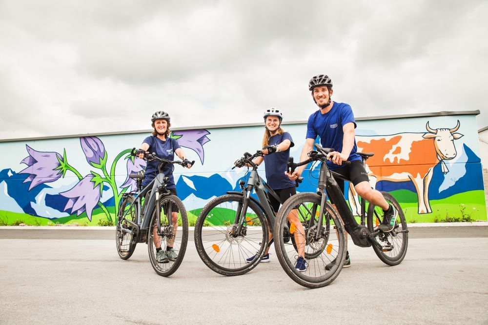 Drei Personen auf E-Mountainbikes vor einer Graffiti-Wand